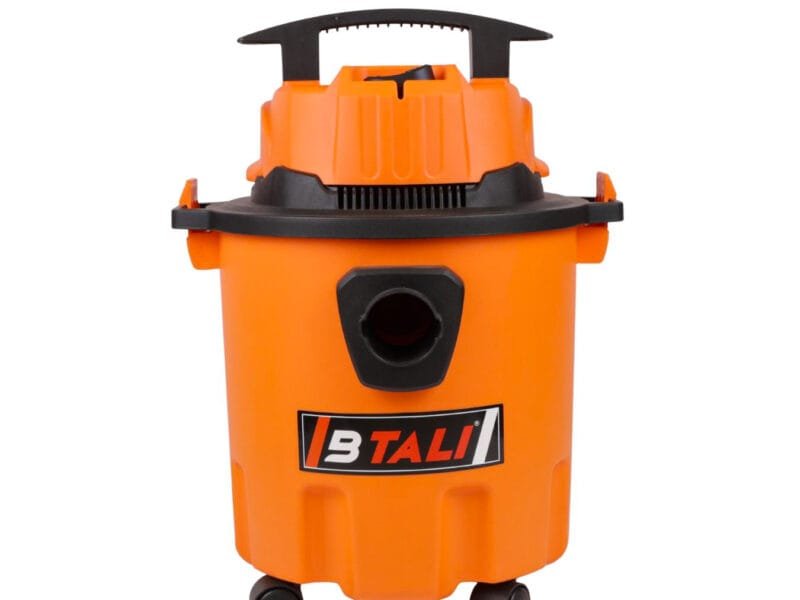 A professional small vacuum cleaner for industrial dust being used in a small workshop for effective floor cleaning.
